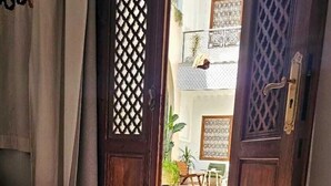 A room with a bed, a wooden door, and a patterned floor. - Riad Jo (Marrakech)