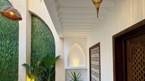 A poolside area with a tiled floor, two wicker chairs, a small round table, and a potted plant. - Riad Jo (Marrakech)