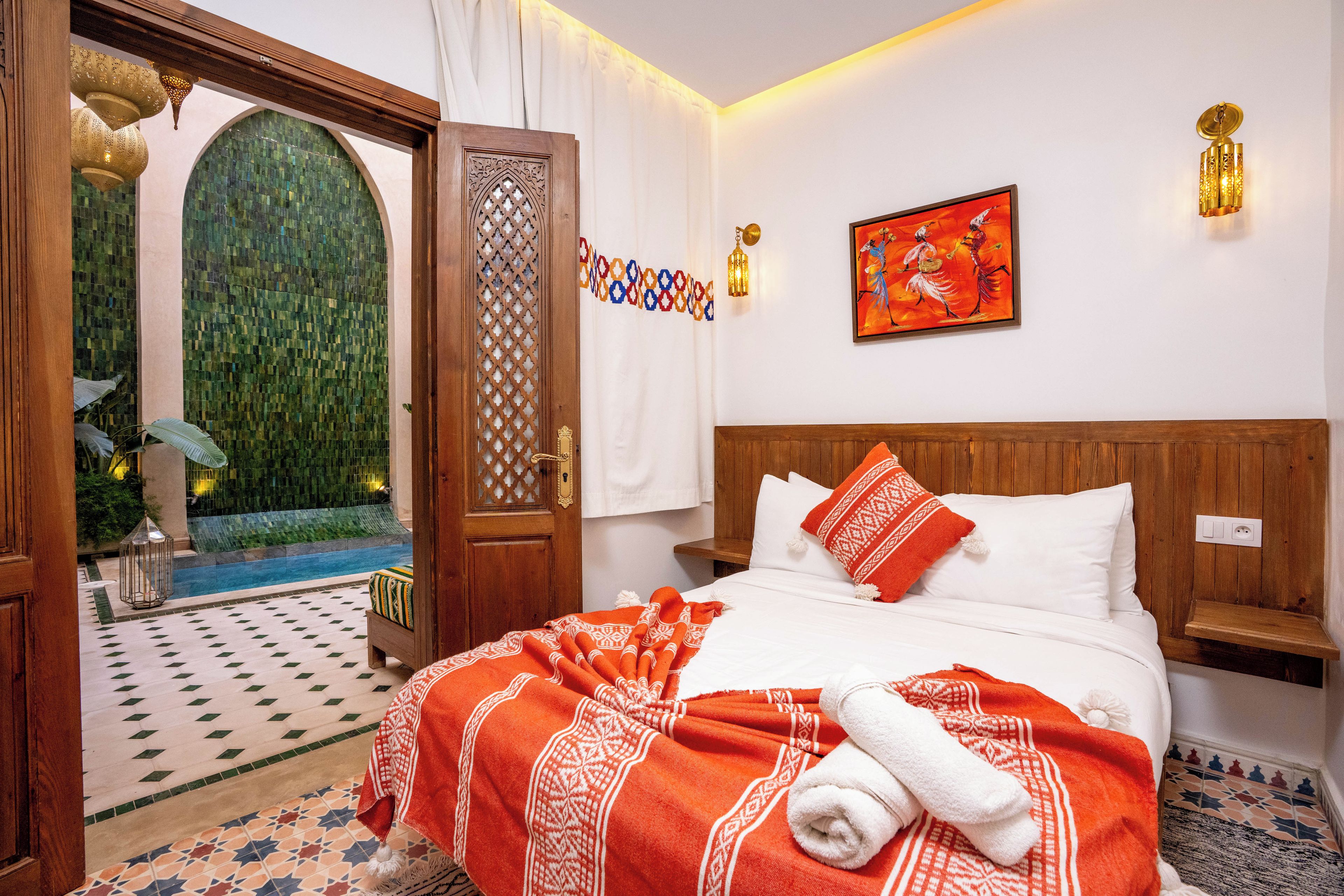 Habitación de hotel con cama, un cuadro, vista a una piscina y una puerta que da a un área exterior.
