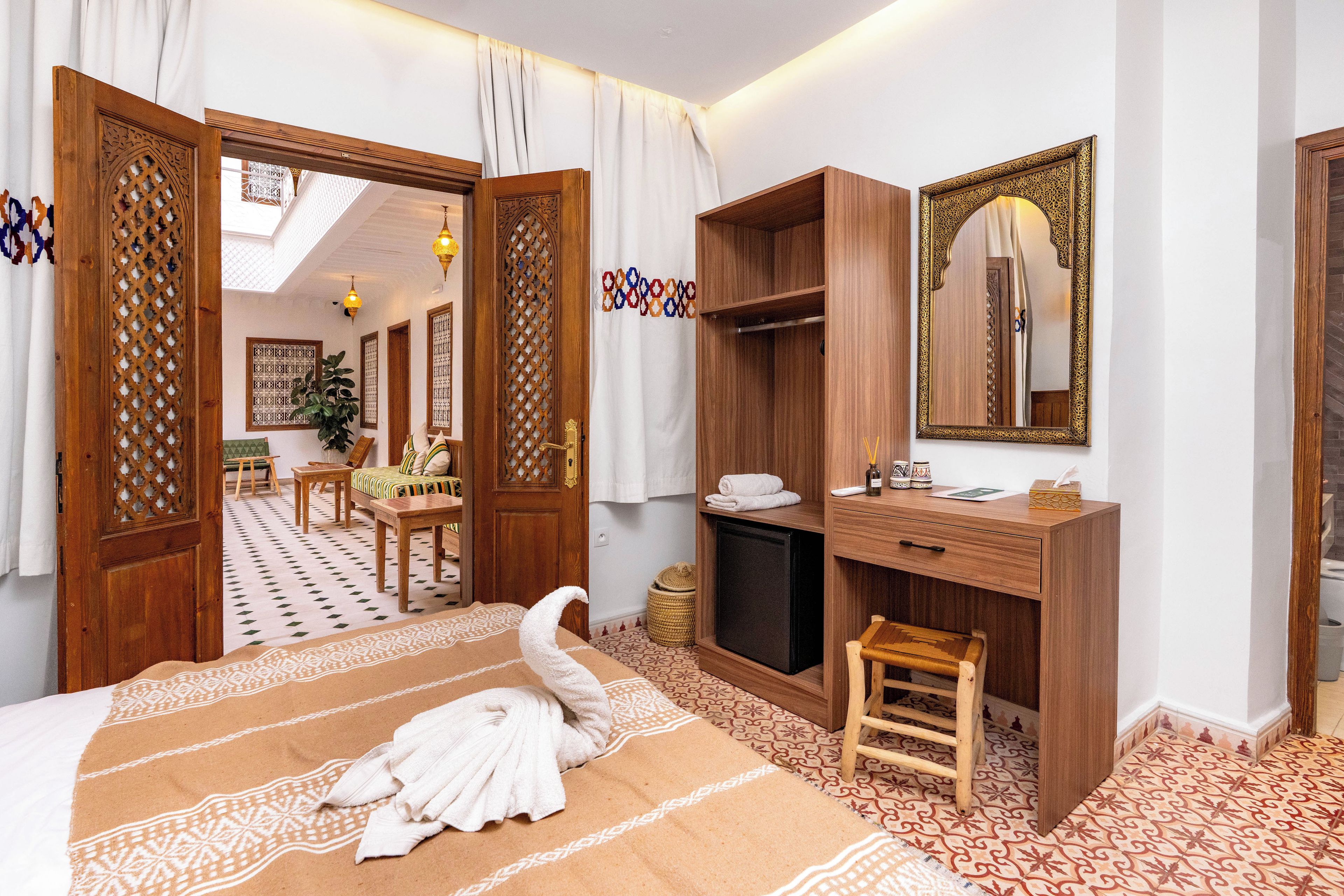 Una habitación de hotel con cama, escritorio de madera, espejo y armario.