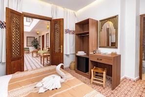 Ein Hotelzimmer mit einem Bett, einem Holztisch, einem Spiegel und einem Kleiderschrank.