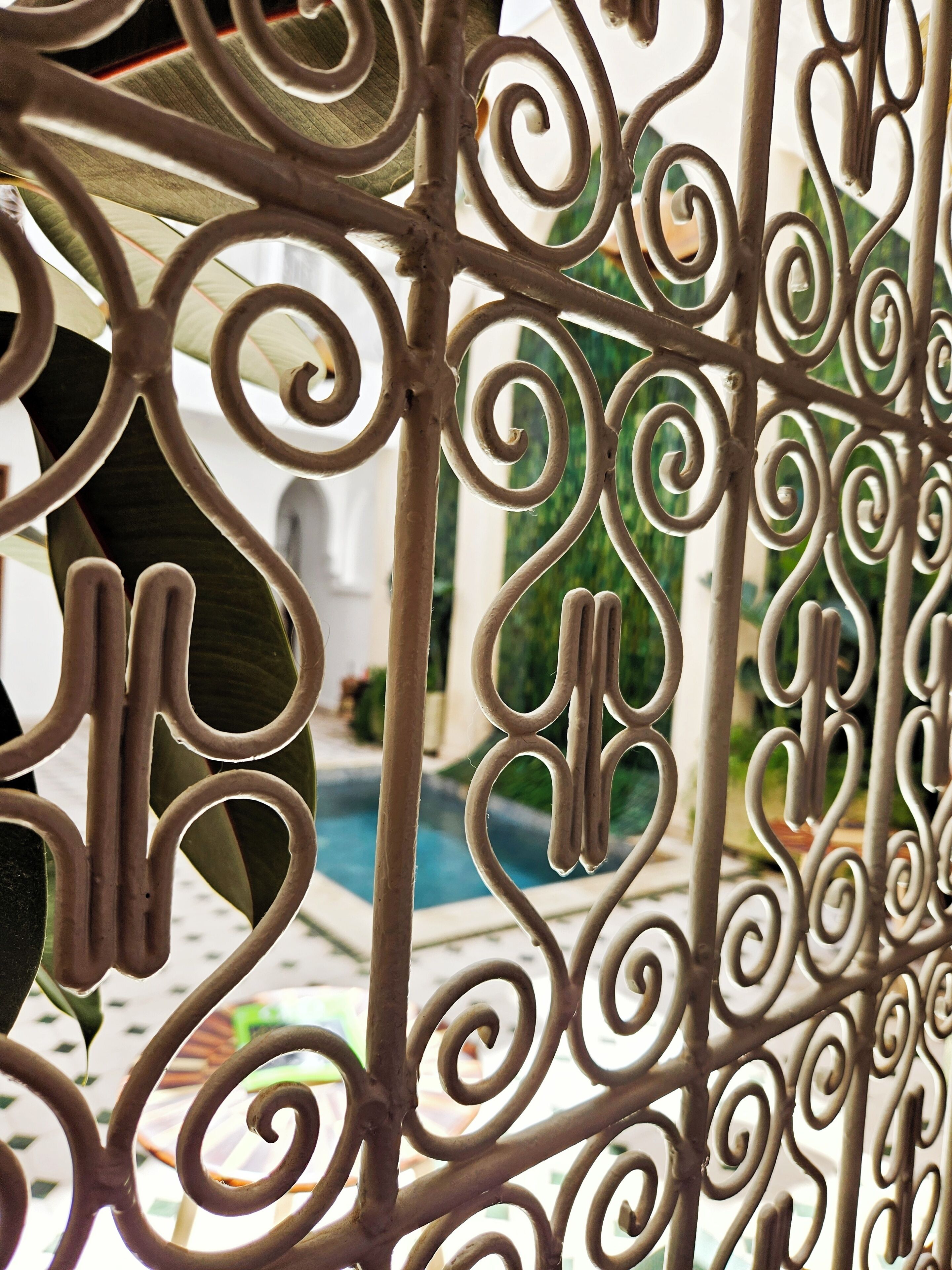 A close-up of ornate metal railings with a pool in the background.