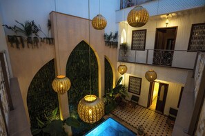 Un intérieur à plusieurs niveaux, agrémenté d’arcades, de lanternes suspendues et d’un espace piscine.