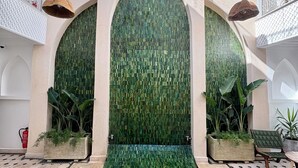 A pool area with a tiled floor, a central water feature, and two large arched walls with mosaic tiles. - Riad Jo (Marrakech)