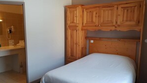 A bedroom with a wooden headboard, a bed with white bedding, and a bathroom visible through an open door. - Auberge Communale - La Fruitière Péron (Péron)