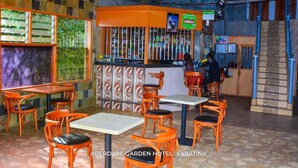 A restaurant area with orange chairs and tables, a bar with a patterned wall, and a staircase with blue railings. - Aberdare gardens and resort karatina (Karatina)