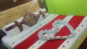 A bed with a red and white striped bedspread, a decorative pillow, and a white blanket with heart patterns. - Aberdare gardens and resort karatina (Karatina)