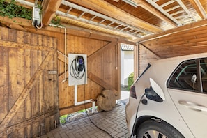 A vehicle charging station, a wooden door, and a brick floor.