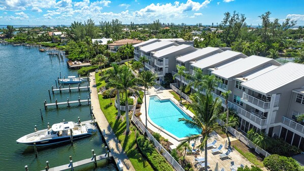 A resort with a swimming pool, docked boats, and a view of the surrounding area. - Chic coastal living meets resort-style amenities! (Longboat Key)