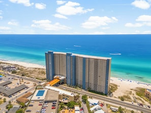 Ein Hochhaus-Hotel mit mehreren Etagen, einem Parkplatz und einer Strandlage.