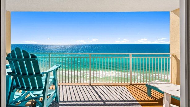 Uma varanda com vista para o oceano, um deck de madeira e um par de cadeiras Adirondack.