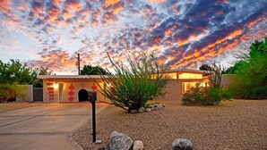 A modern house with a driveway leading to a garage, surrounded by a gravel area with rocks and a small bush. - 30+ Stay! Perfect For Families, W/Pool & Hot Tub (Palm Springs)