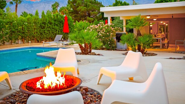 A poolside area with a fire pit, lounge chairs, and a building with a pool. - 30+ Stay! Perfect For Families, W/Pool & Hot Tub (Palm Springs)