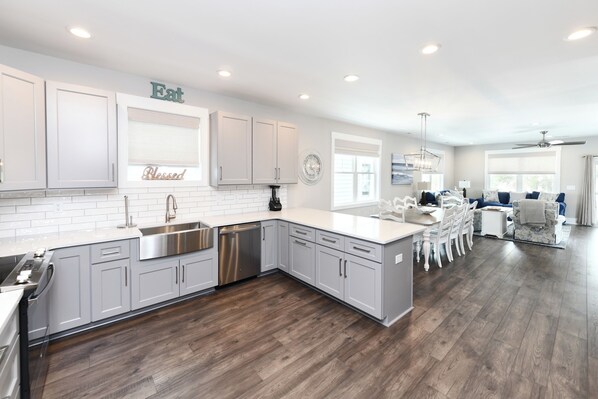 A modern kitchen with white cabinets, stainless steel appliances, and a wooden floor. - 5 Bedroom, Private Pool, Elevator - New Construction - Why Knot (Surfside Beach)