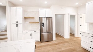 Eine moderne Küche mit weißen Schränken, einem Edelstahlkühlschrank und Holzböden.