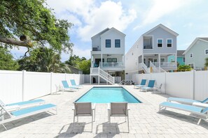 A two-story house with a swimming pool, white fences, and blue lounge chairs. - 5 Bedroom, Private Pool, Elevator - New Construction - Why Knot (Surfside Beach)