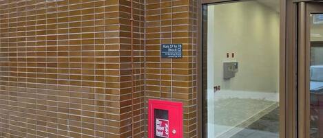 A building with a tiled facade, a security camera, a fire alarm, and a sign indicating flats 57 to 78.