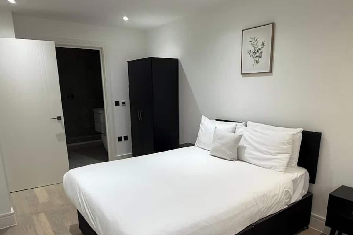 A modern bedroom with a large bed, a wardrobe, and a framed picture on the wall.