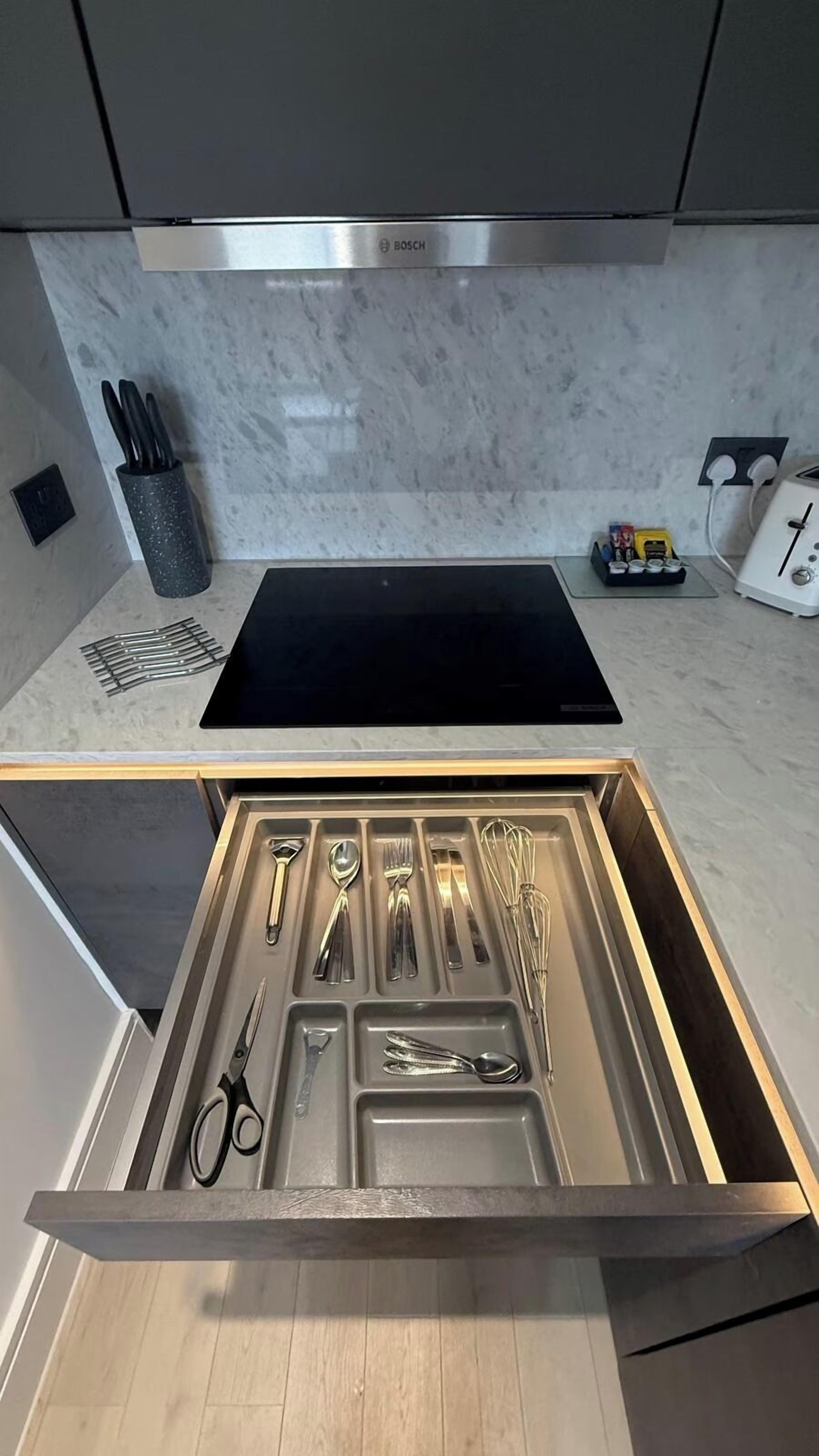A kitchen with a Bosch range hood, a built-in stovetop, and a drawer organizer with utensils.