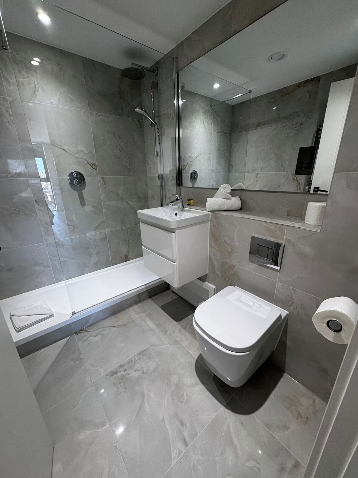 A modern bathroom with a shower, toilet, and sink.