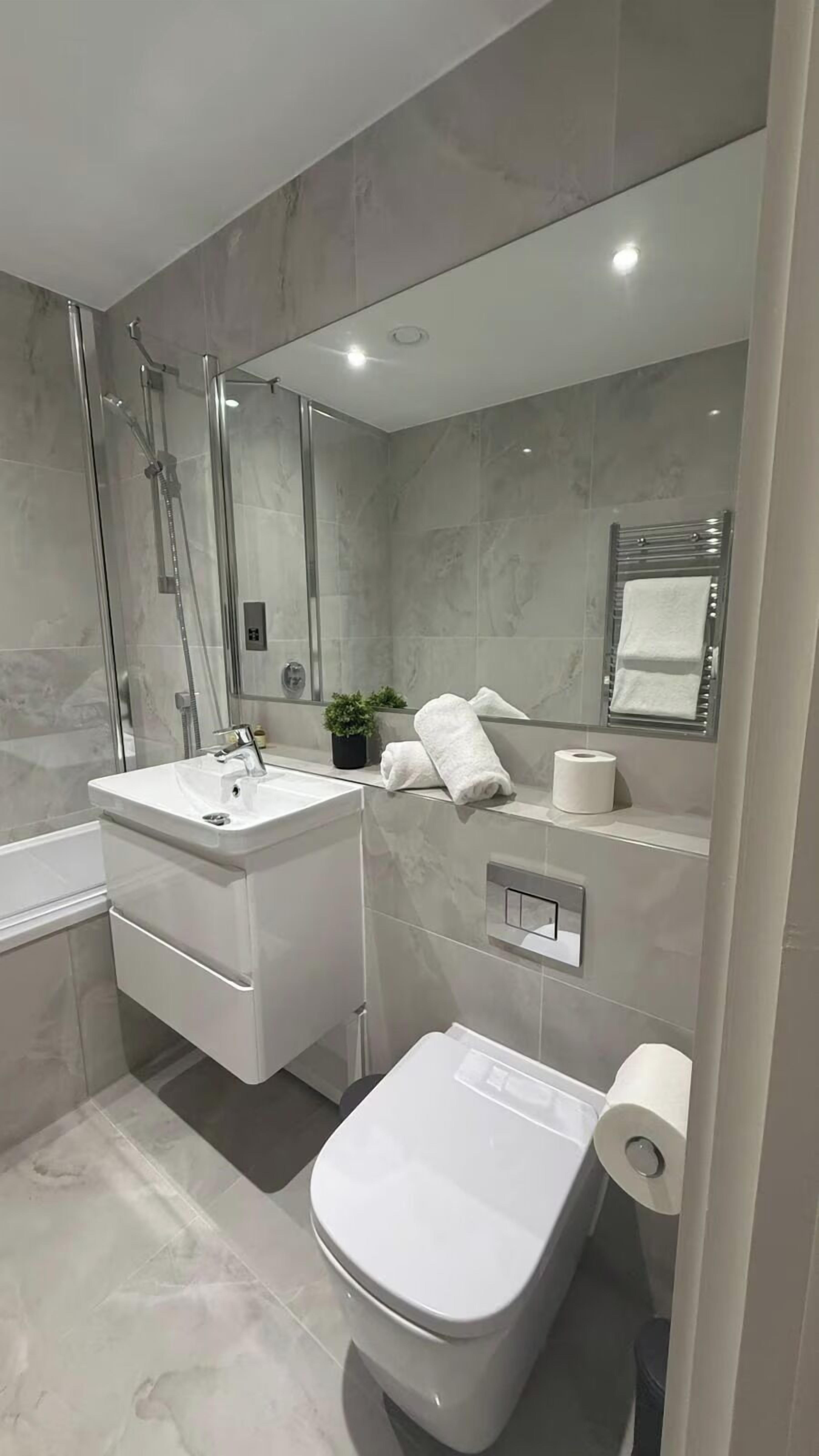 Uma casa de banho moderna com chuveiro em cabine de vidro, lavatório branco e sanita.