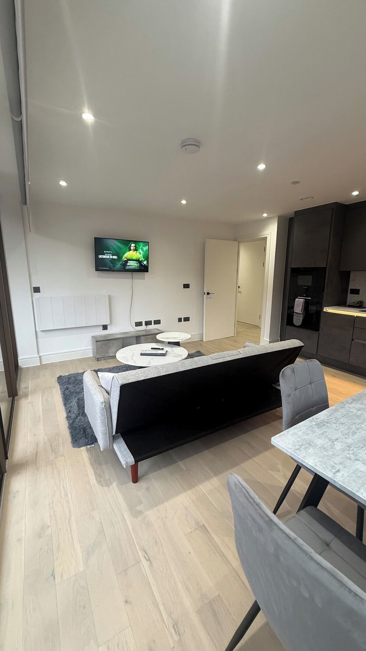 Una cocina moderna con una isla central, un comedor con mesa y sillas, y un televisor de pantalla plana montado en la pared.