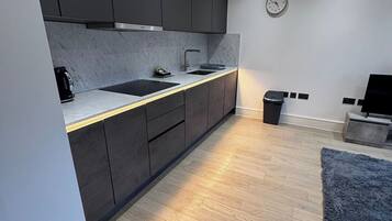 Una cocina moderna con armarios oscuros, encimera de mármol y suelo de madera.