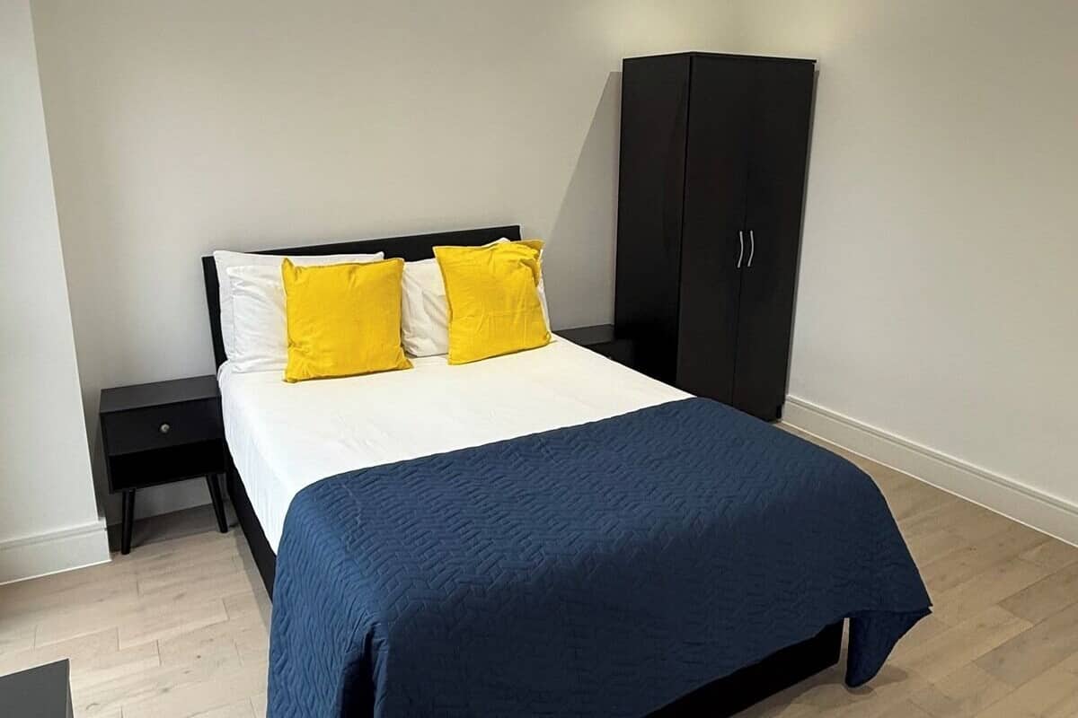 A bedroom with a bed, a nightstand, a wardrobe, and a flat-screen TV.