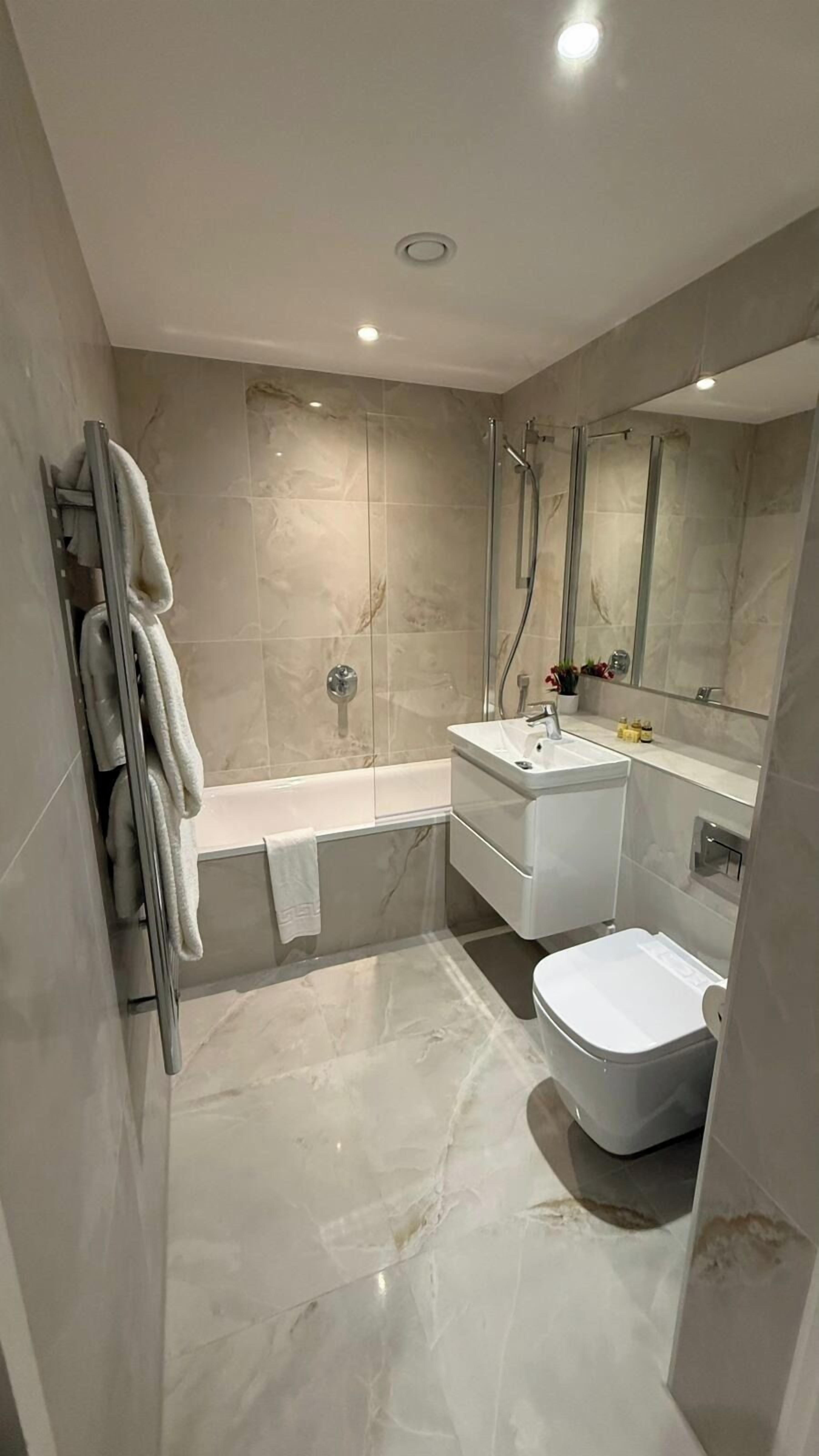 A modern bathroom with a glass-enclosed shower, a white sink, and a toilet.
