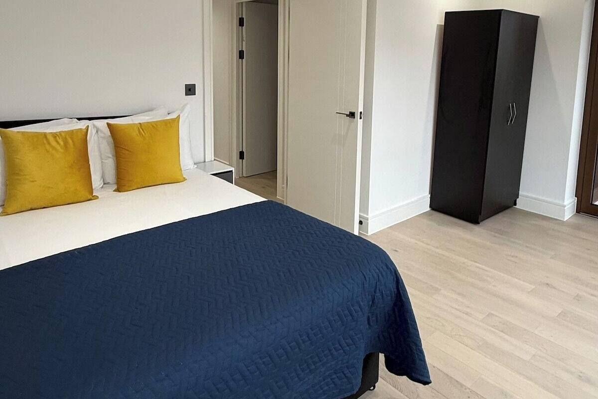 A bedroom with a bed, a wardrobe, and a door leading to another room.