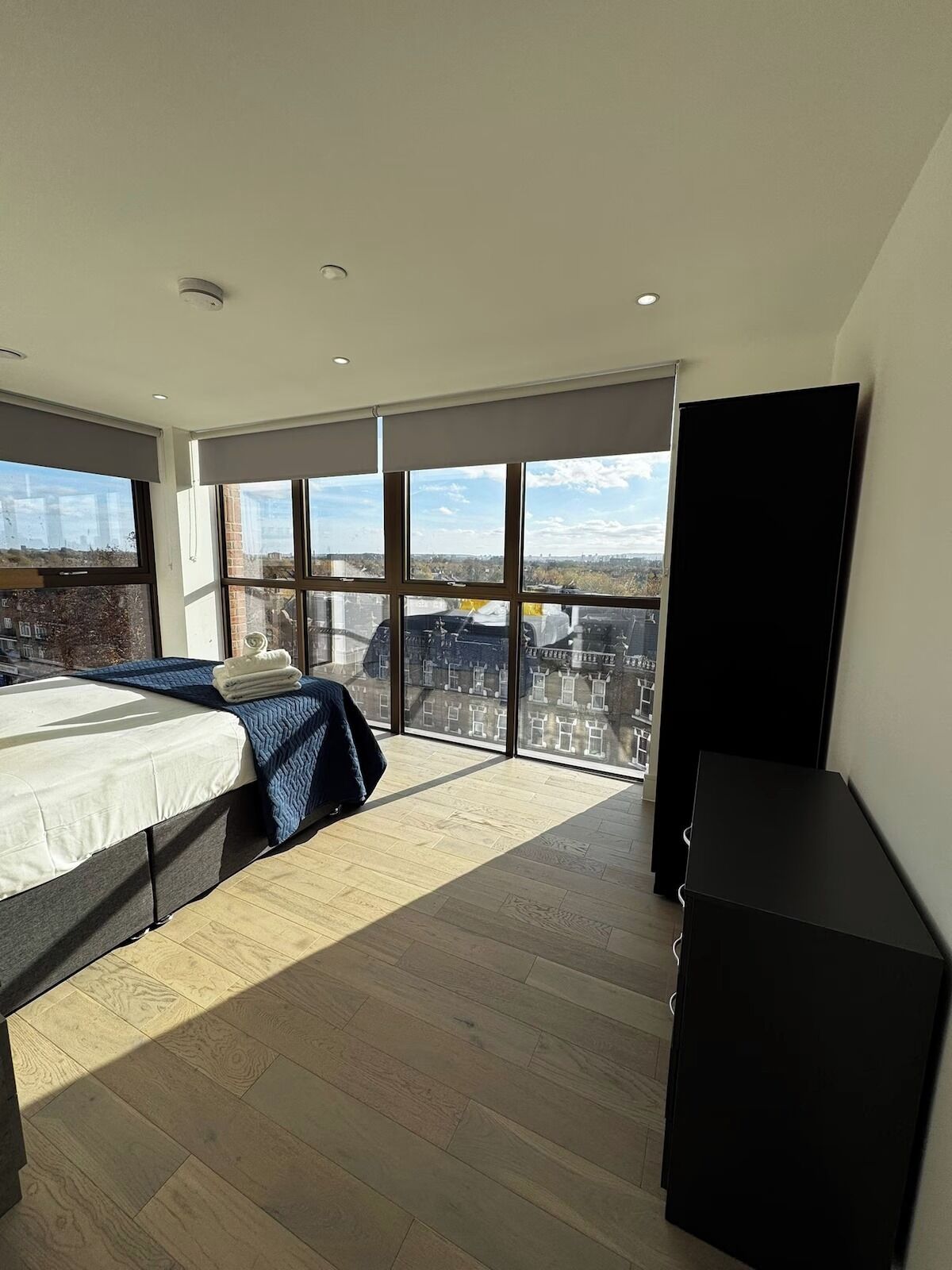 Une chambre moderne dotée d’un grand lit, d’un téléviseur à écran plat et d’un balcon offrant une vue sur la ville.
