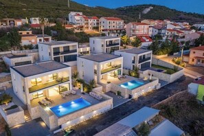 Ein modernes Wohngebiet mit mehreren zweigeschossigen Häusern, jeweils mit Pool und Außenbereichen zum Verweilen.