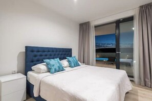 Ein Schlafzimmer mit einem großen Bett, einem Nachttisch und einer Glastür, die auf einen Balkon führt.