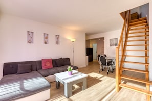 Een moderne woonkamer met een bank, een salontafel, een trap en een eethoek.