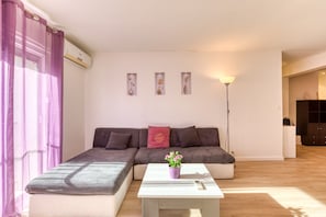 Een woonkamer met een bank, een salontafel en een potplant.