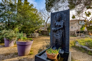 Ein Garten mit Statue, Topfpflanzen und Gartenmöbeln.