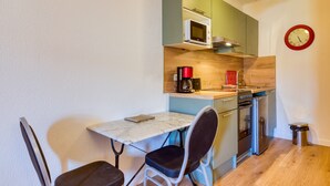 Una cocina compacta equipada con microondas, cafetera y lavamanos.