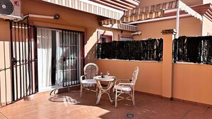 Un balcón con dos sillones de mimbre, una mesita redonda y una barandilla decorativa.