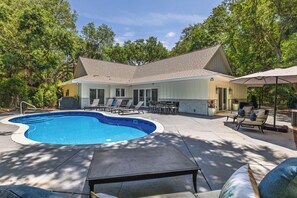 A pool area with a swimming pool, lounge chairs, and a covered patio.