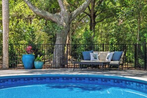 A swimming pool with a surrounding patio area, a seating arrangement, and large potted plants. - Abalone Alley 04 - Easy Breezy  - Private Pool (Isle Of Palms)
