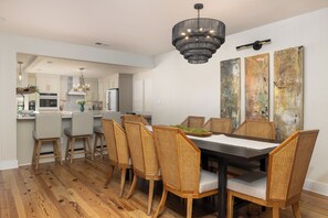 Un comedor con mesa de madera oscura, sillas de mimbre y una lámpara moderna.