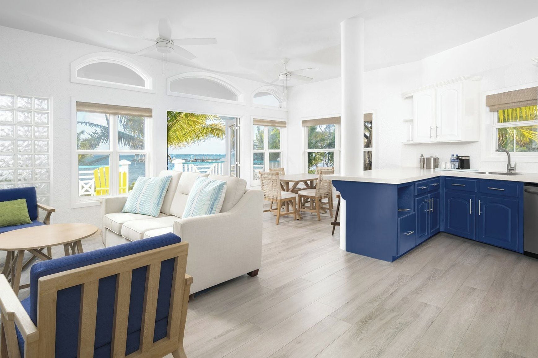 A spacious living area with a white sofa, a dining table with chairs, and a kitchen with blue cabinets.