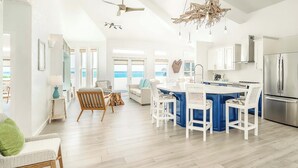 A bright kitchen with a central island, white cabinetry, and a stainless steel refrigerator. - Reef Haven Belize (San Pedro)
