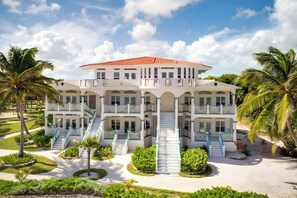A large, multi-story hotel with a symmetrical facade, multiple balconies, and a central staircase. - Reef Haven Belize (San Pedro)