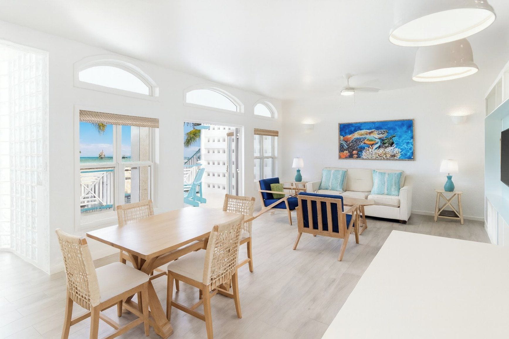 A bright living room with a dining area, a sofa, and a painting.
