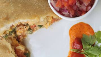 A plate with a piece of food, a bowl of sauce, and a bowl of diced vegetables.