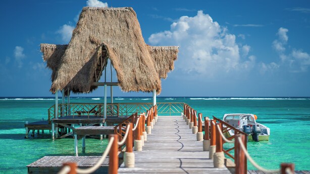 A wooden pier leading to a thatched-roof structure over turquoise waters. - Reef Haven Belize (San Pedro)