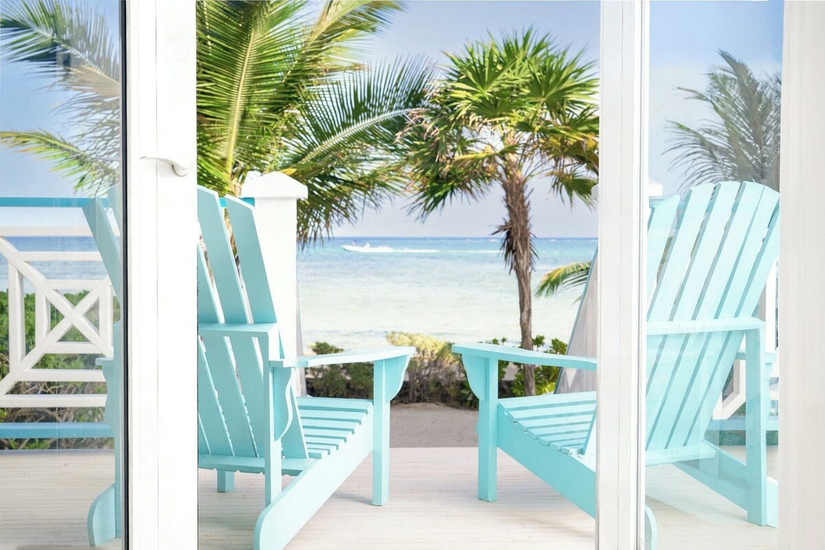 A deck with turquoise chairs and a view of the ocean.