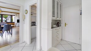 Uma cozinha moderna com armários brancos, micro-ondas e cafeteira.