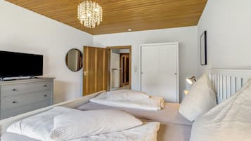Ein Schlafzimmer mit einem Bett, einem Schminktisch, einem Fernseher und einer Kristallleuchter.